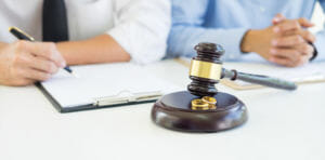 Two people signing divorce papers with a gavel in front of them