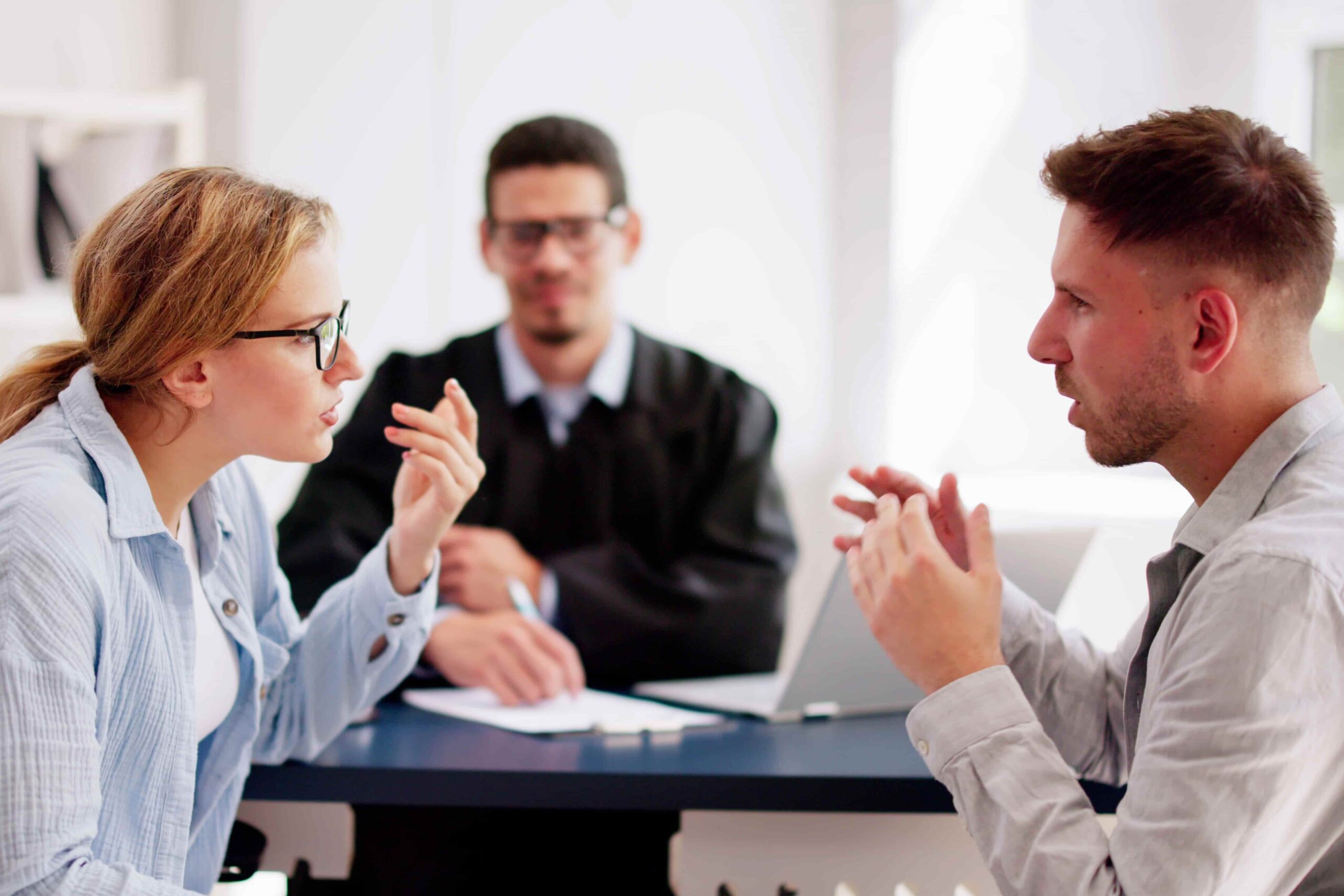 Couple arguing during a mediation session with a lawyer or counselor facilitating the discussion.
