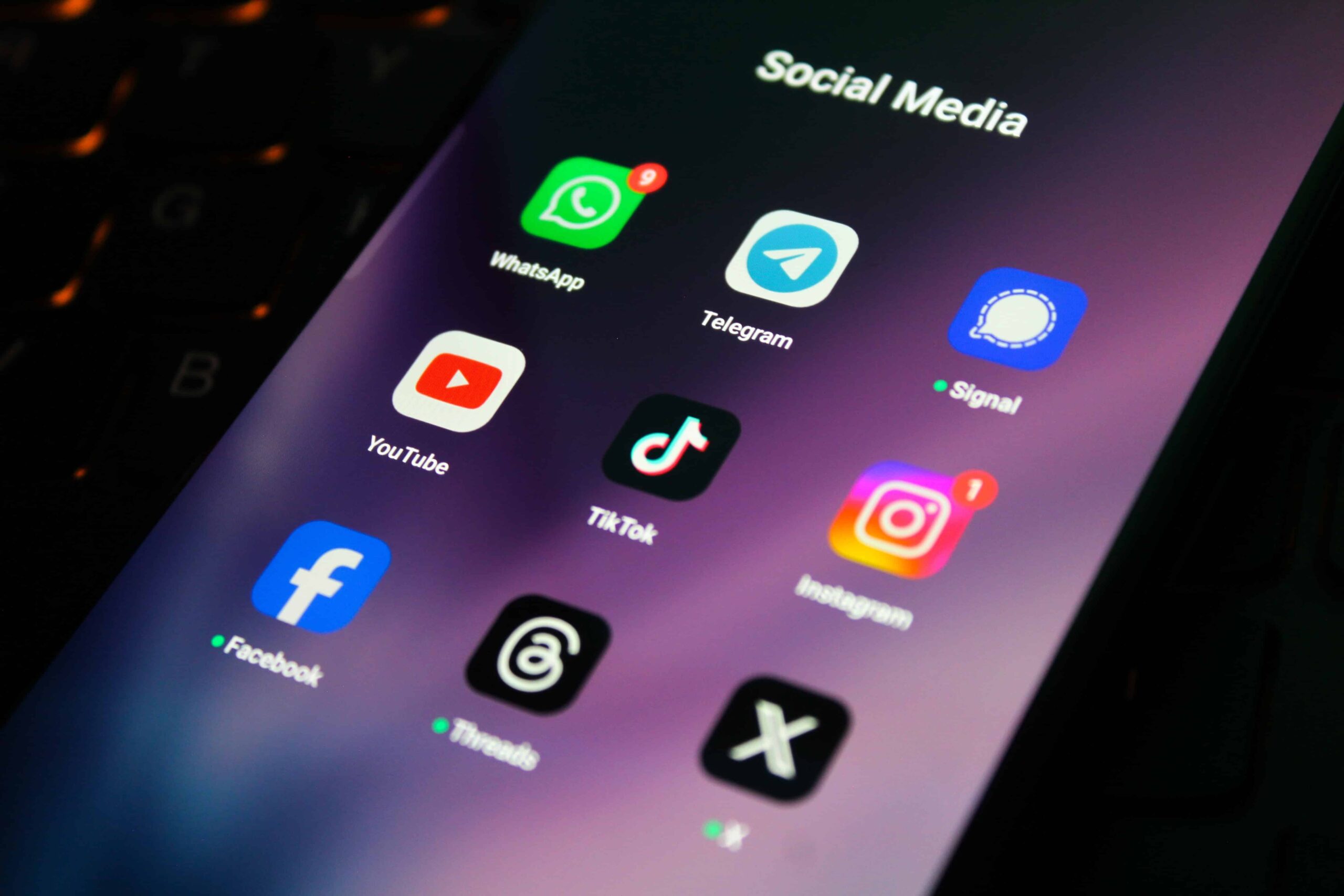 Smartphone screen showing social media and messaging apps including Facebook, Instagram, TikTok, YouTube, WhatsApp, Telegram, Signal, Threads, and X.