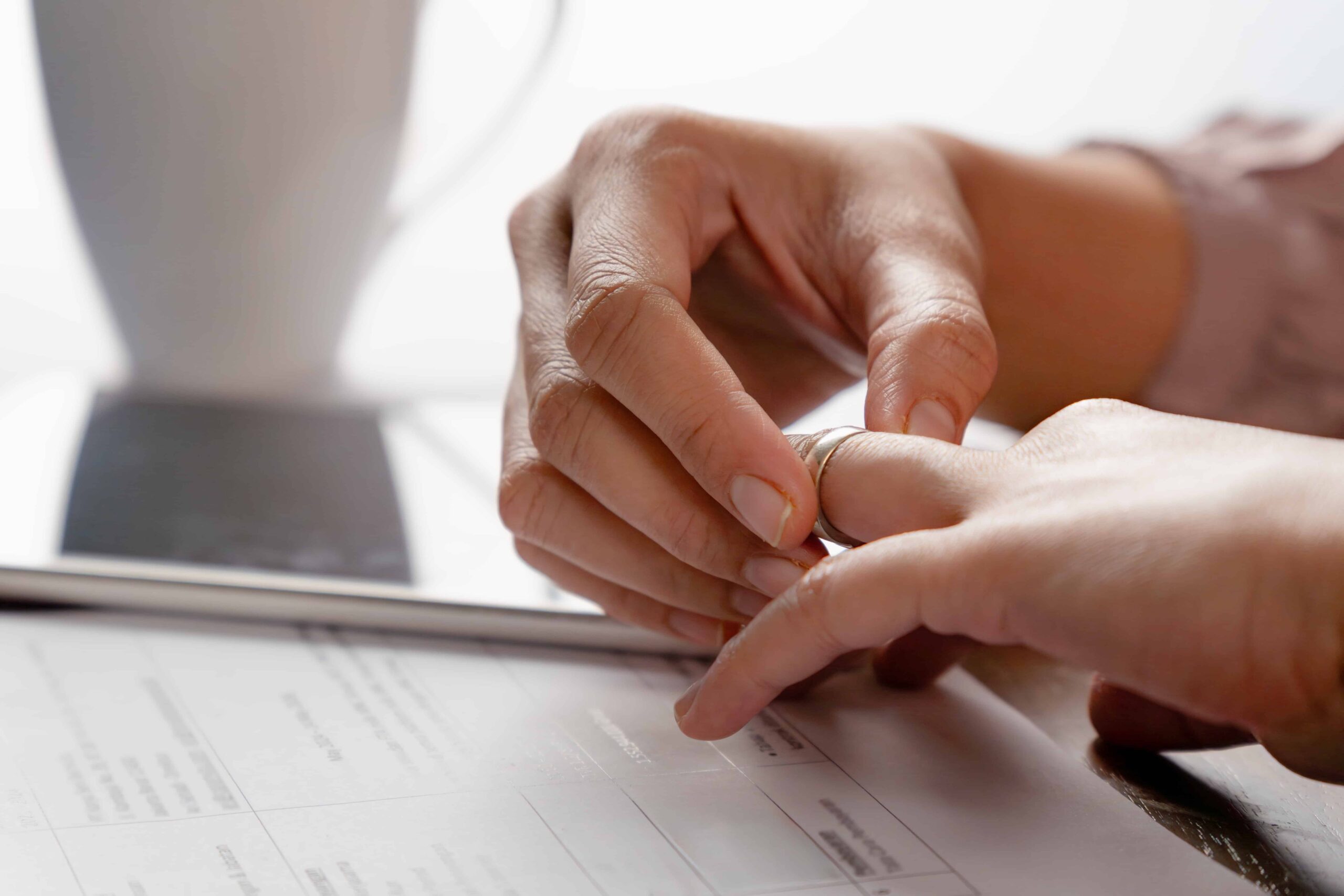 Close-up of a person removing a wedding ring while reviewing legal paperwork, symbolizing divorce or separation